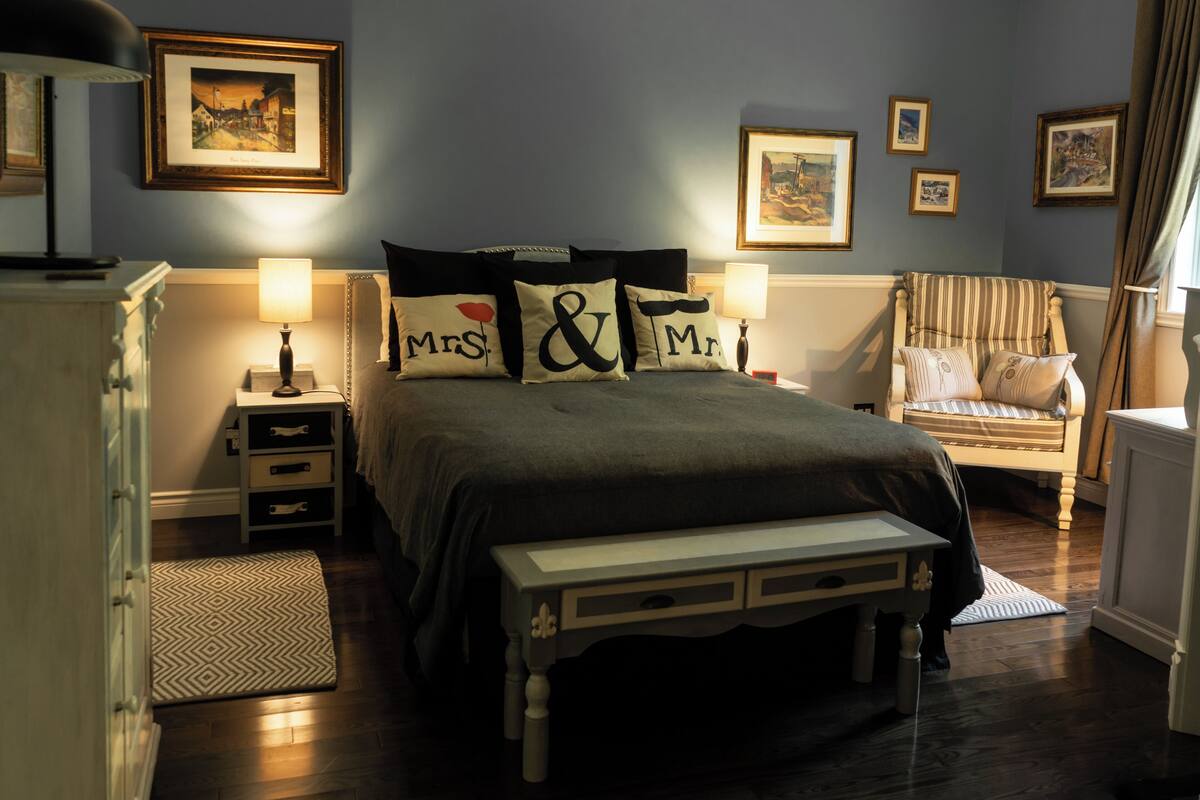 Une chambre à coucher comprenant un lit, des tables de chevet, une chaise et une commode.