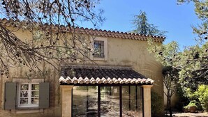 A rustic building with a tiled roof, a covered patio area, and a window with shutters.