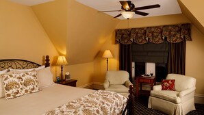 A hotel room with a bed, two armchairs, a nightstand, a lamp, and a ceiling fan. - Experience a relaxing, cozy and friendly stay. Walking distance to downtown! (KALAMAZOO)