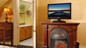 A room with a fireplace, a television on a stand, a wooden dresser, and a mirror on the wall. - Experience a relaxing, cozy and friendly stay. Walking distance to downtown! (KALAMAZOO)