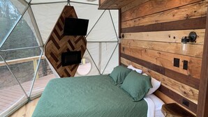 A cozy bedroom with a bed, pillows, and a wooden headboard. - Moonshiner Tree Dome is rustic luxury with big, beautiful panoramic views. (Hico)