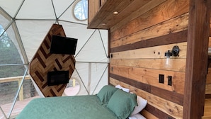 A cozy bed with a green quilt, a wooden headboard, and a small bedside table. - Moonshiner Tree Dome is rustic luxury with big, beautiful panoramic views. (Hico)