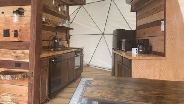 A compact kitchen with wooden cabinets, a sink, and a microwave. - Moonshiner Tree Dome is rustic luxury with big, beautiful panoramic views. (Hico)