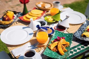 A breakfast table with plates, a glass of orange juice, and various food items. - Villa Dar Minzah (Marrakech)