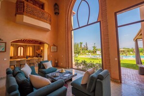 A spacious living area with a balcony, a dining area, and a view of a pool. - Villa Dar Minzah (Marrakech)