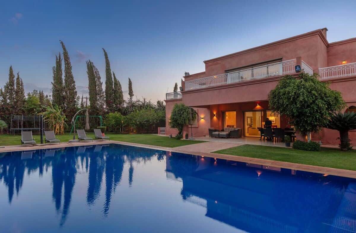 A two-story building with a swimming pool, outdoor seating area, and a well-maintained garden.