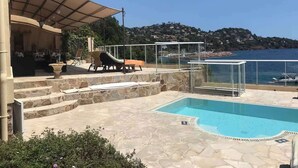 A pool area with a view of the sea, outdoor seating, and a covered patio. - Private beach villa, sea view (Théoule-sur-Mer)