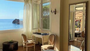 A bedroom with a large window overlooking the sea, a desk with chairs, and a mirror reflecting the room. - Private beach villa, sea view (Théoule-sur-Mer)