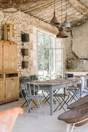 A rustic interior with a stone wall, wooden cabinets, and a large dining table with metal chairs.