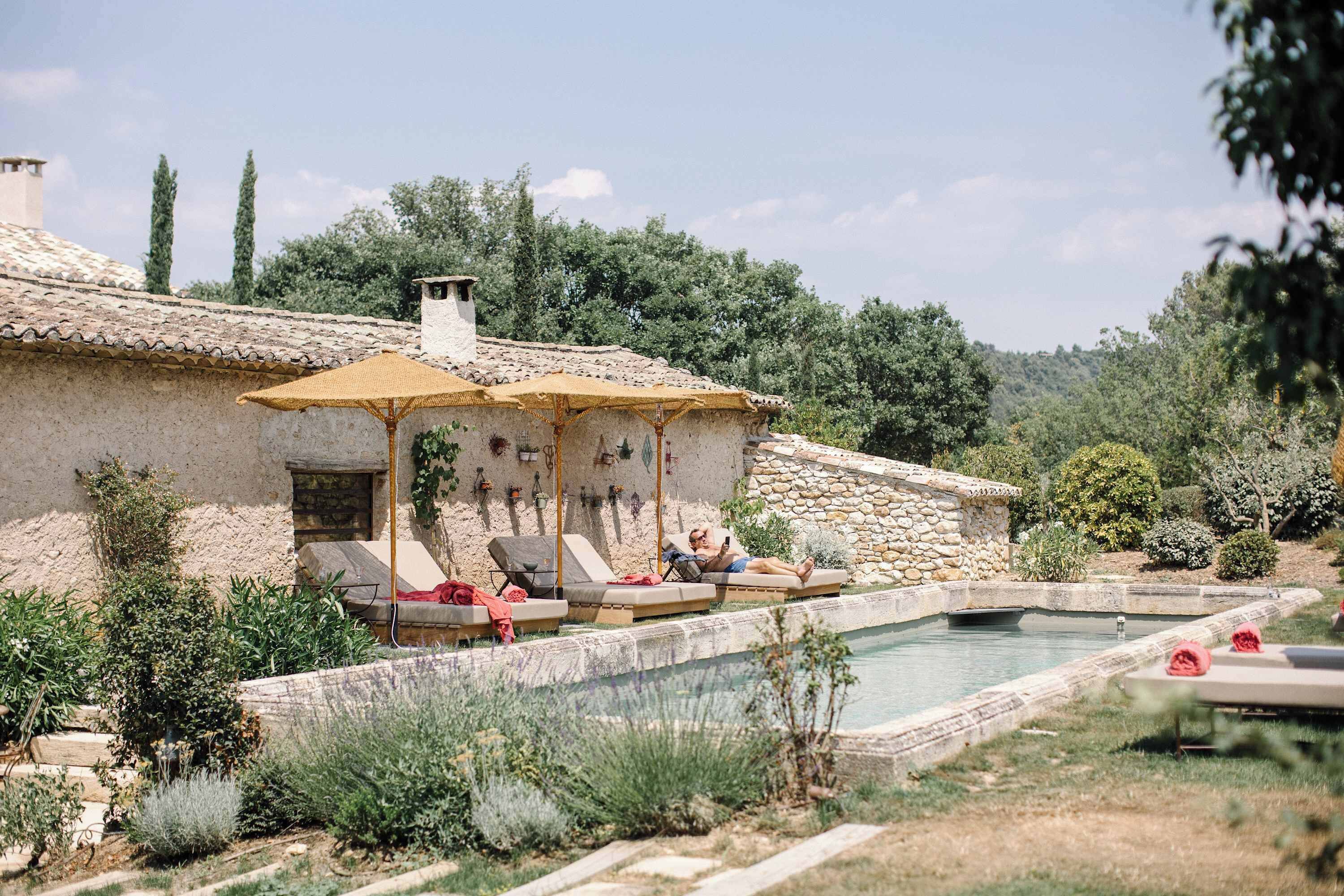 A villa with a swimming pool, outdoor seating, and a garden.