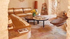 Un intérieur chaleureux et rustique, avec des murs en pierre, une table ronde en bois et un coin salon confortable.