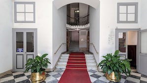 A hotel lobby with a checkered marble floor, a red carpet, and two potted plants. - Corvetto Luxury Suite by Wonderful Italy (Genoa)