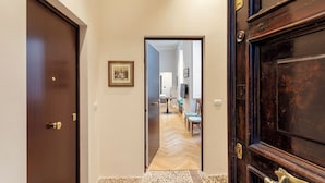 A hallway with a wooden door on the left, a framed picture on the wall, and a view into a dining area with a table and chairs. - Corvetto Luxury Suite by Wonderful Italy (Genoa)