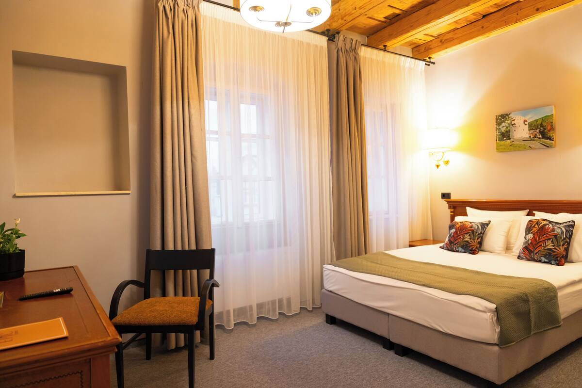 Una habitación de hotel con cama, una silla, un escritorio y un cuadro en la pared.