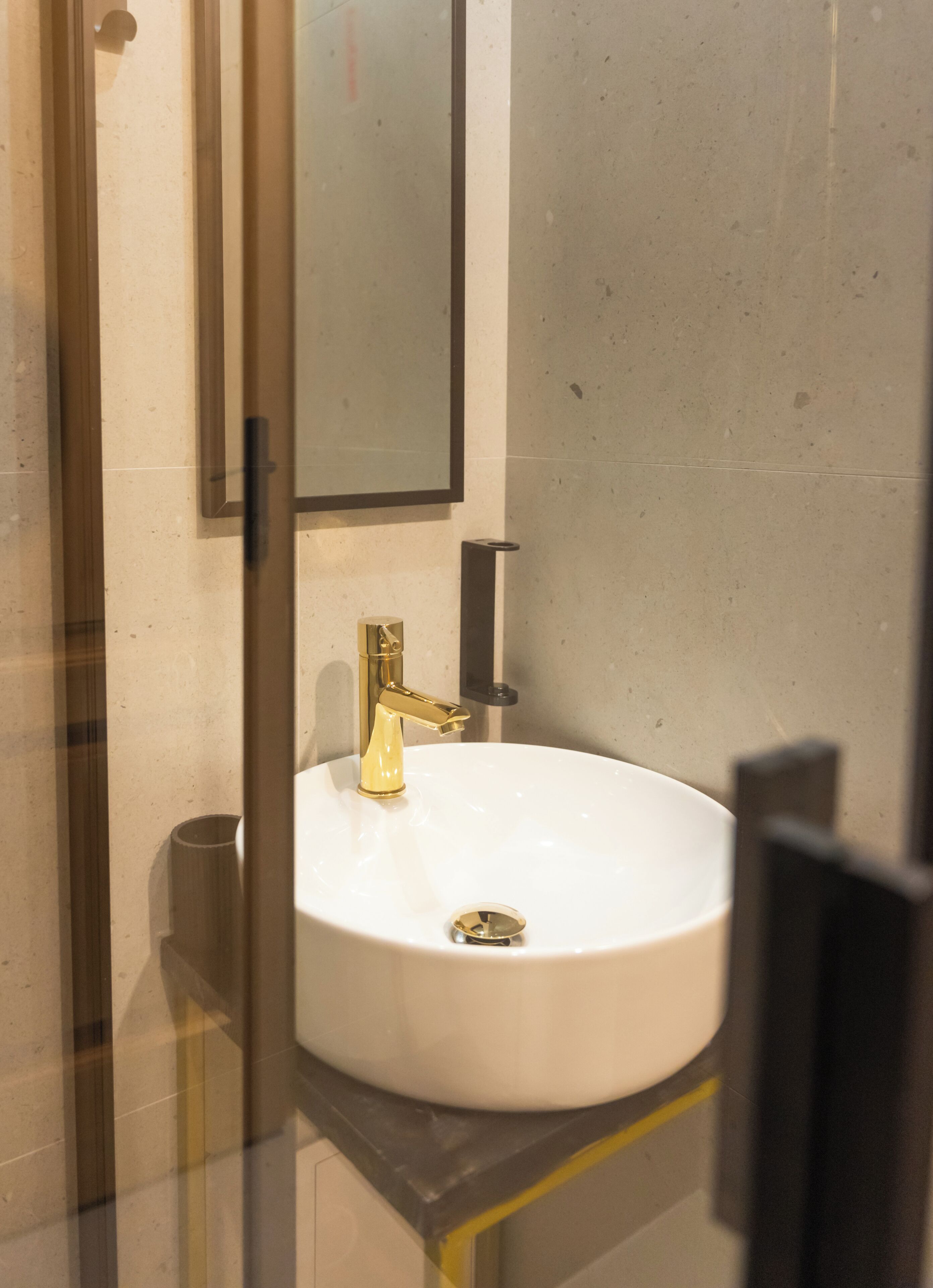 Un baño con lavamanos blanco, grifo dorado y espejo arriba.