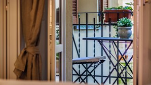 Ein Balkon mit Tisch und Stühlen, Blumentöpfen und Blick auf die Straße.