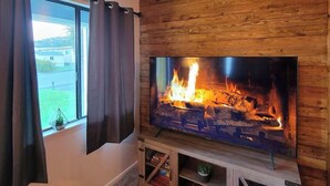 A living room with a fireplace, a window with curtains, and a small plant on the windowsill.