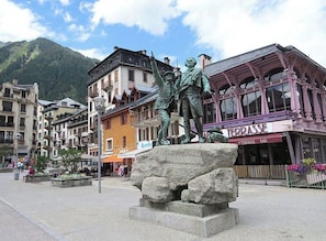A public square with a statue, buildings, and a bar.