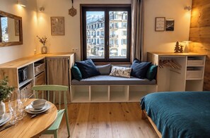 A cozy room with a built-in bench seating area, a dining table with chairs, and a bed with a green cover.