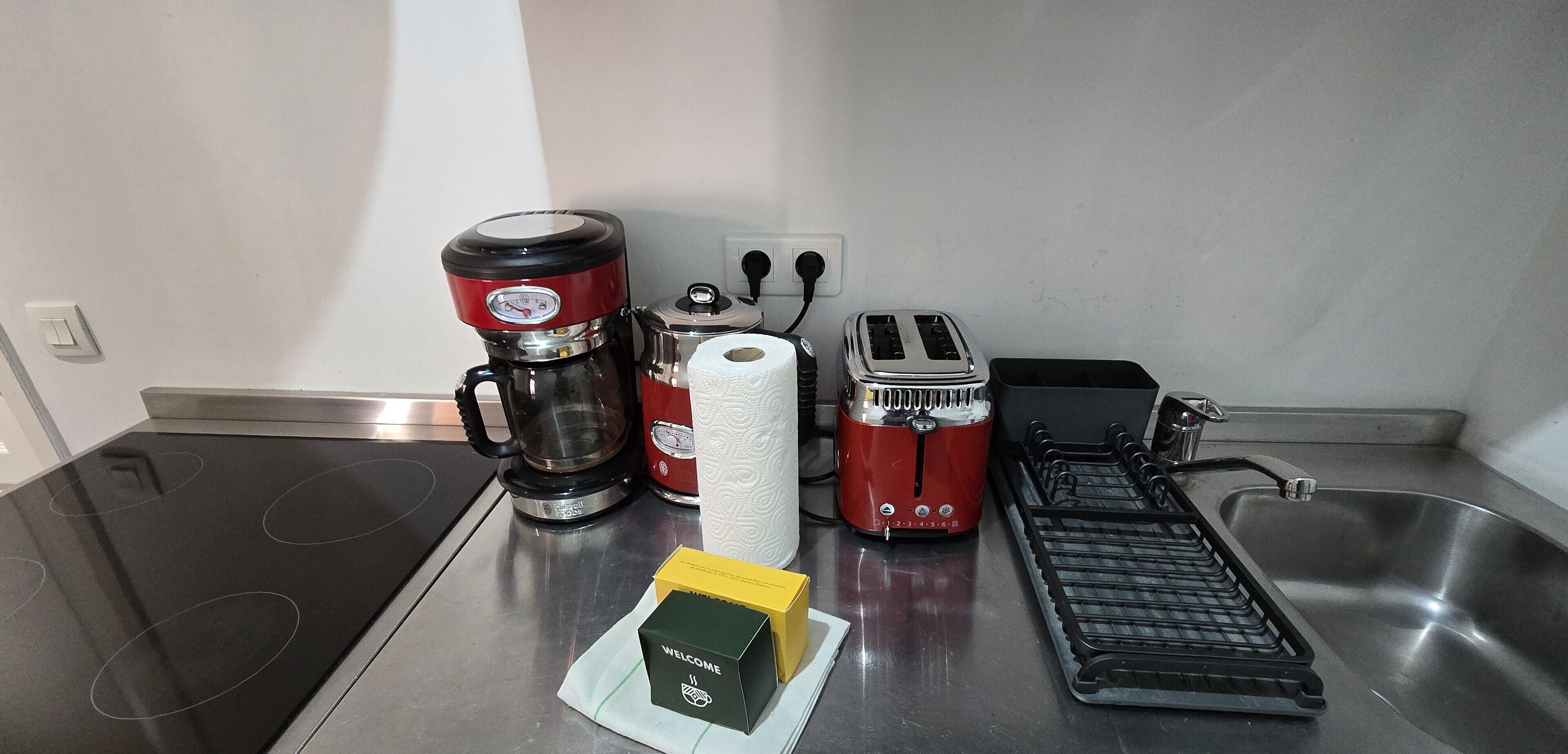Een keuken met een koffiezetapparaat, broodrooster en waterkoker op het aanrecht.