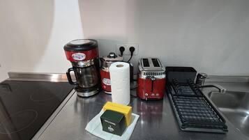 Een keuken met een koffiezetapparaat, broodrooster en waterkoker op het aanrecht.