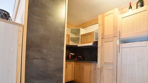 A kitchen with wooden cabinets, a coffee maker, and a refrigerator.