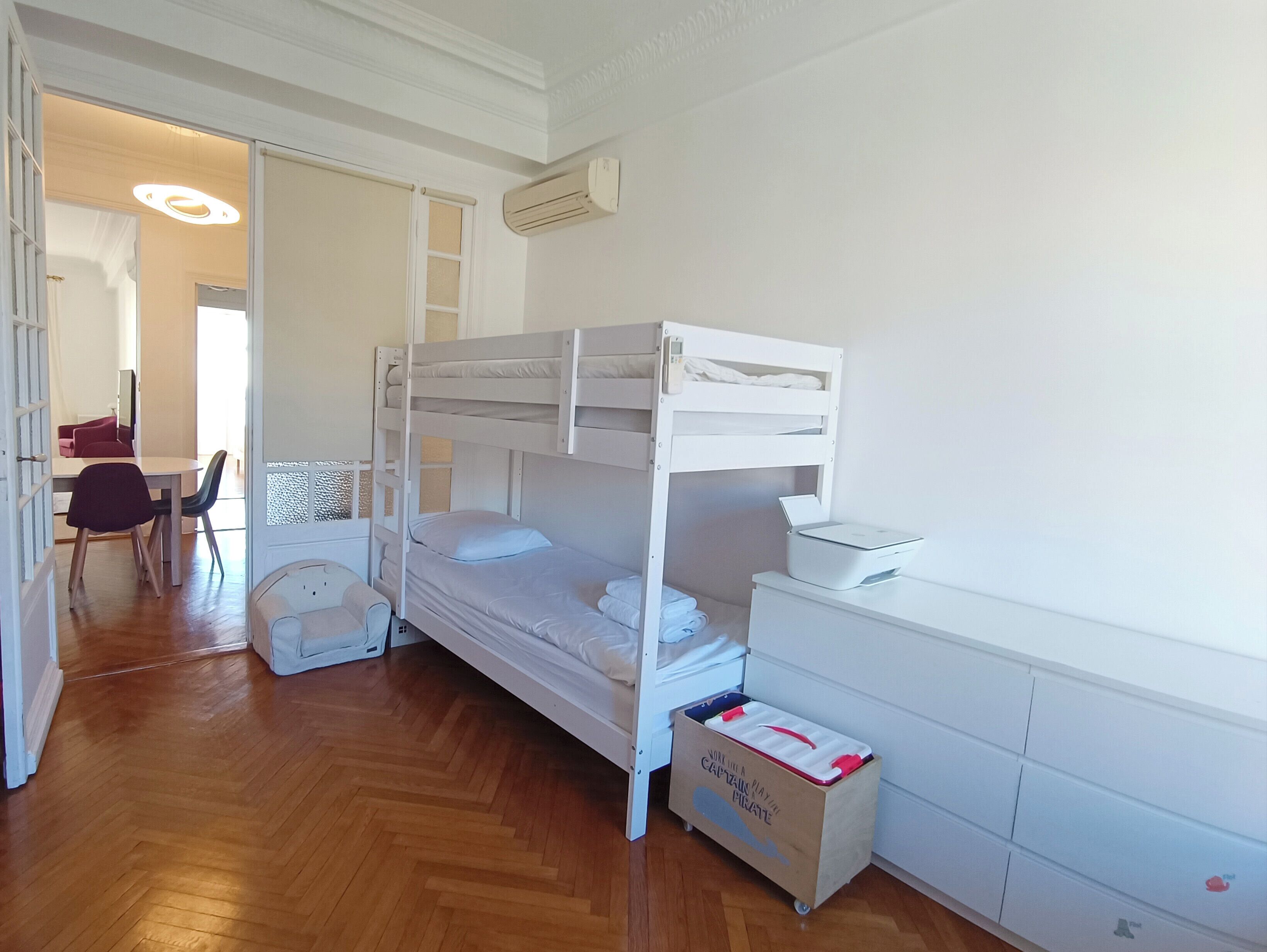 Une chambre avec un lit superposé, un bureau, une chaise et une petite boîte de rangement étiquetée « Capitaine Pirate ».