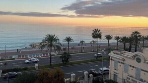 A coastal road with palm trees, a beach, and a building with a clock tower. - Bright T3 - near the beach (Nice)