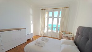 A bedroom with a bed, a dresser, and a view of the sea through large windows. - Bright T3 - near the beach (Nice)