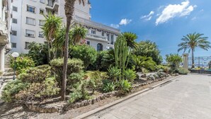A hotel with a modern facade, a landscaped garden with various plants, and a clear sky. - Bright T3 - near the beach (Nice)