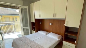 A bedroom with a bed, wardrobe, and a balcony. - Holiday apartment with internet and balcony (Bibione)
