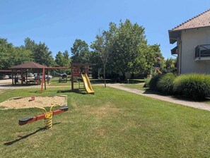 Ein Spielplatz mit Rutsche, Schaukeln, einem Picknicktisch und einem Pavillon.