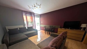 Una sala moderna con un conjunto de sofá, televisión y comedor.