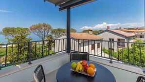 Un balcón con una mesa dispuesta con fruta, vistas a casas y cielo despejado.