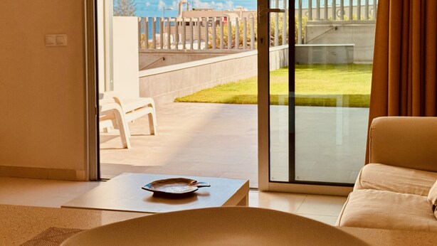 A modern living room with a large glass door leading to an outdoor patio.