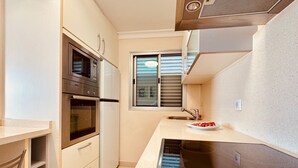 A compact kitchen with a built-in oven, a microwave, a sink, and a stovetop.