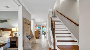 A hotel hallway with a staircase, a bed, a nightstand, a bench, and a door leading to another room. - Pickleball Courts, 30A, Pools, Beach Accesses (Santa Rosa Beach)