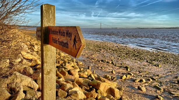 A wooden signpost on a rocky beach with a bridge in the background. - Stylish cottage in vibrant riverside village (North Ferriby)