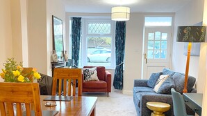 A living room with a wooden dining table, a blue sofa, a red armchair, and a lamp. - Stylish cottage in vibrant riverside village (North Ferriby)