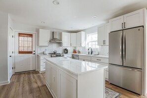 Une cuisine moderne avec des meubles blancs, un réfrigérateur en acier inoxydable et un îlot central.