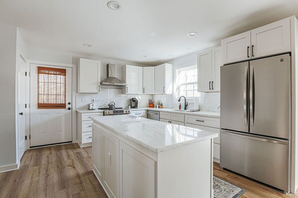 A modern kitchen with white cabinetry, a stainless steel refrigerator, and a central island.