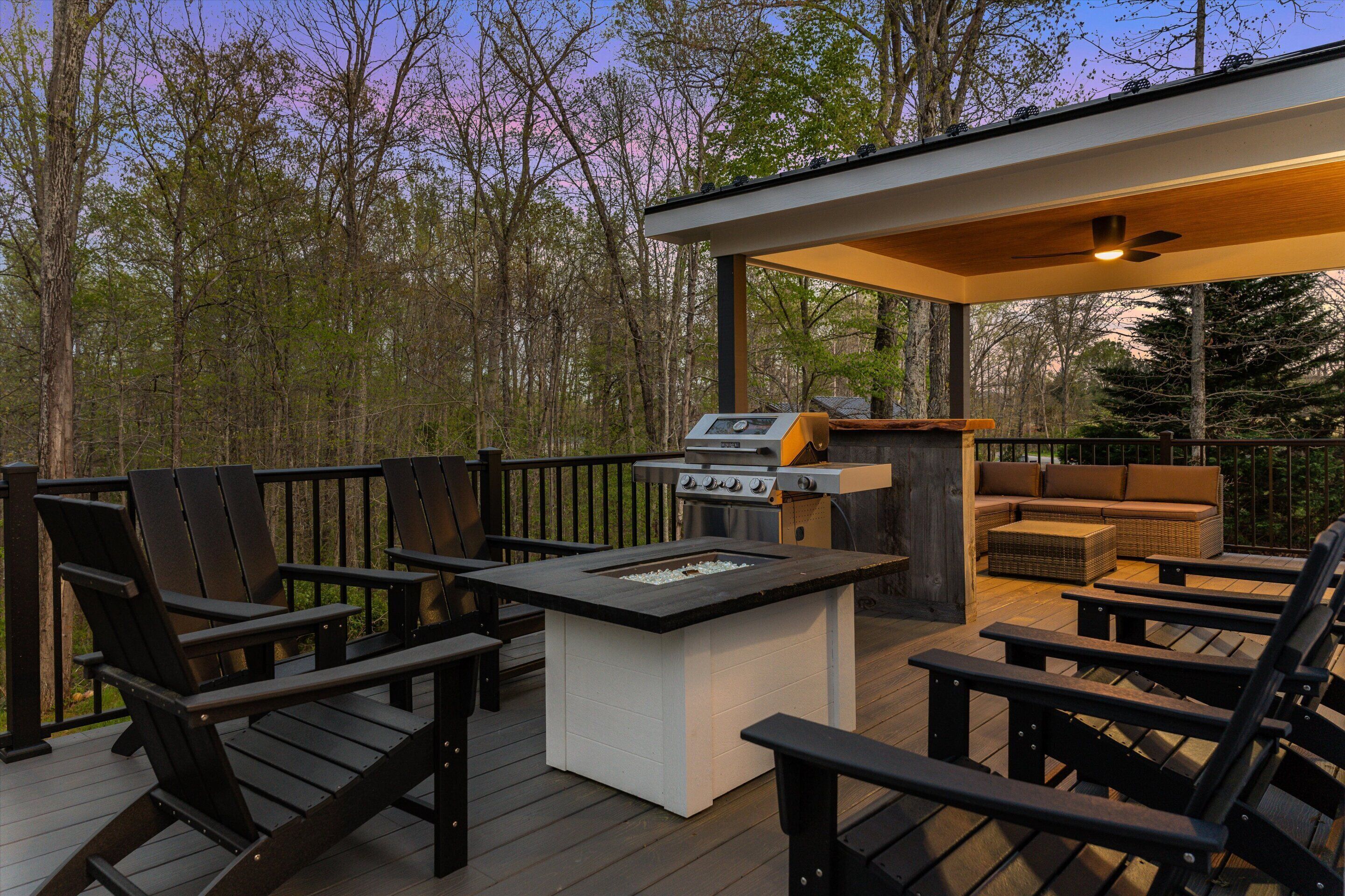 Een terras buiten met een barbecue, zitgedeelte en uitzicht op het omliggende bos.