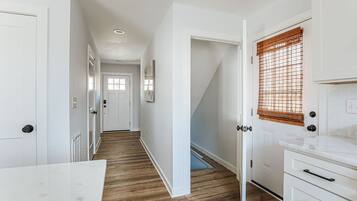 Un couloir aux murs blancs, au plancher en bois et aux meubles de rangement blancs.