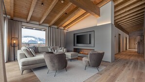A modern living room with a large sofa, armchairs, and a flat-screen TV. - Apartment in Tyrol Near ski Area (Westendorf)