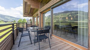 A wooden deck with outdoor seating and large windows overlooking a mountainous landscape. - Apartment in Tyrol Near ski Area (Westendorf)