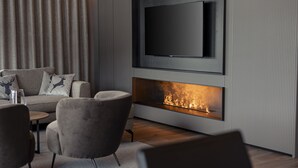 A modern living room with a flat-screen TV mounted on the wall, a built-in fireplace, and a sofa with decorative pillows. - Apartment in Tyrol Near ski Area (Westendorf)