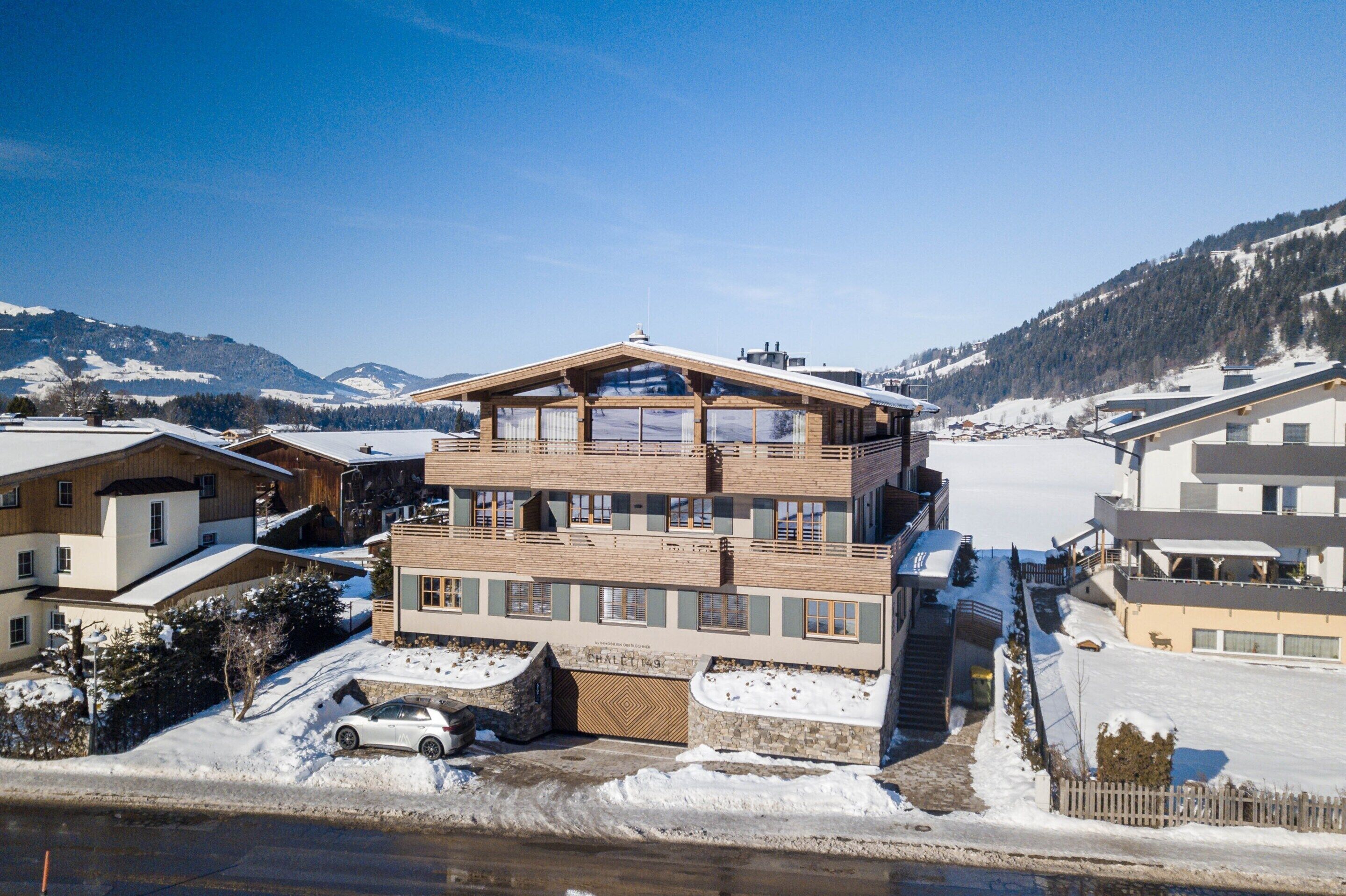 A multi-story building with a wooden facade and large windows, situated in a snowy mountainous area.