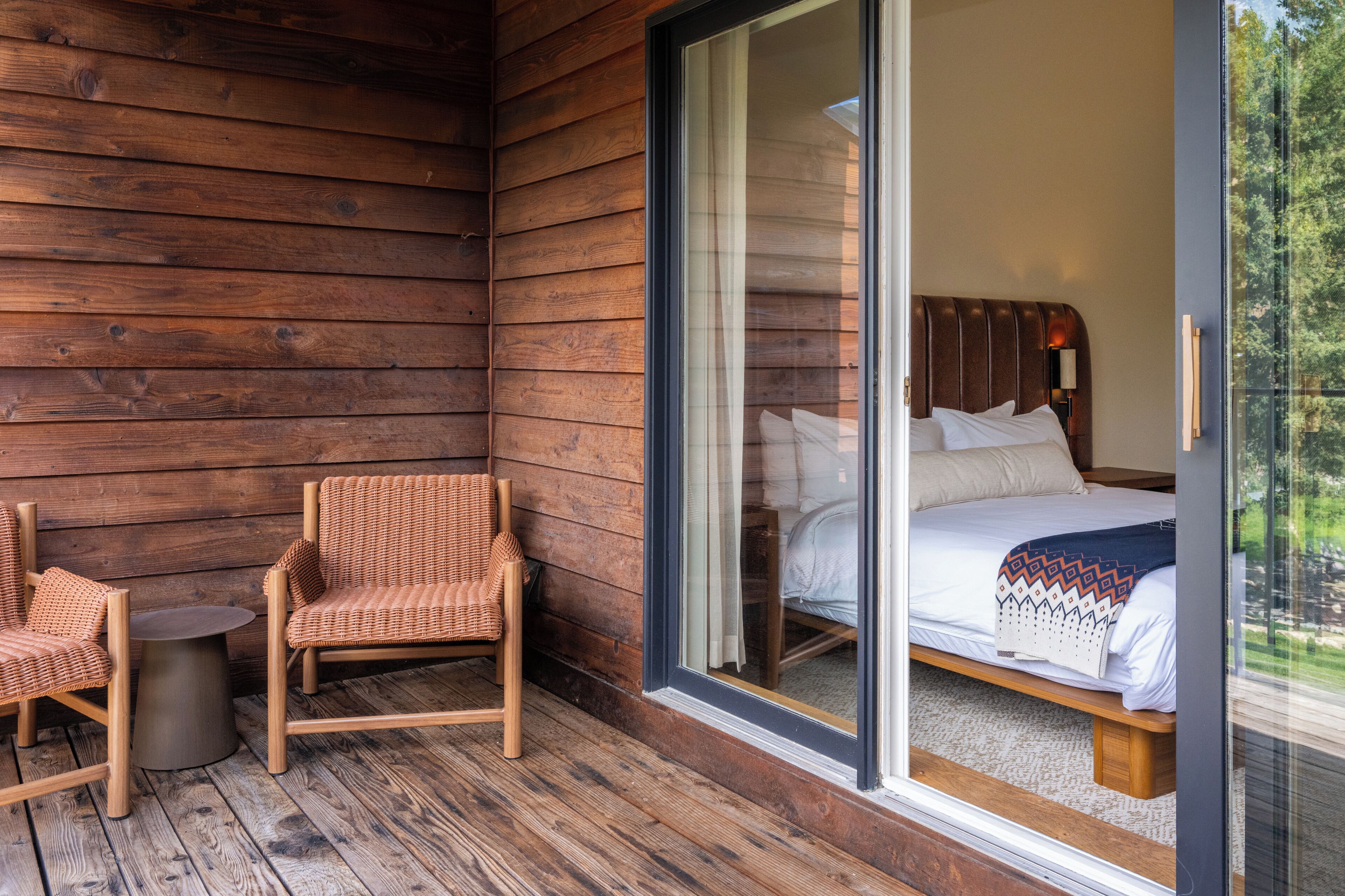 A wooden cabin room with a bed, a chair, and a small table.