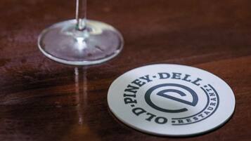 A martini glass with a lime garnish on a wooden bar counter, next to a coaster with 'Piney Dell Restaurant' text.