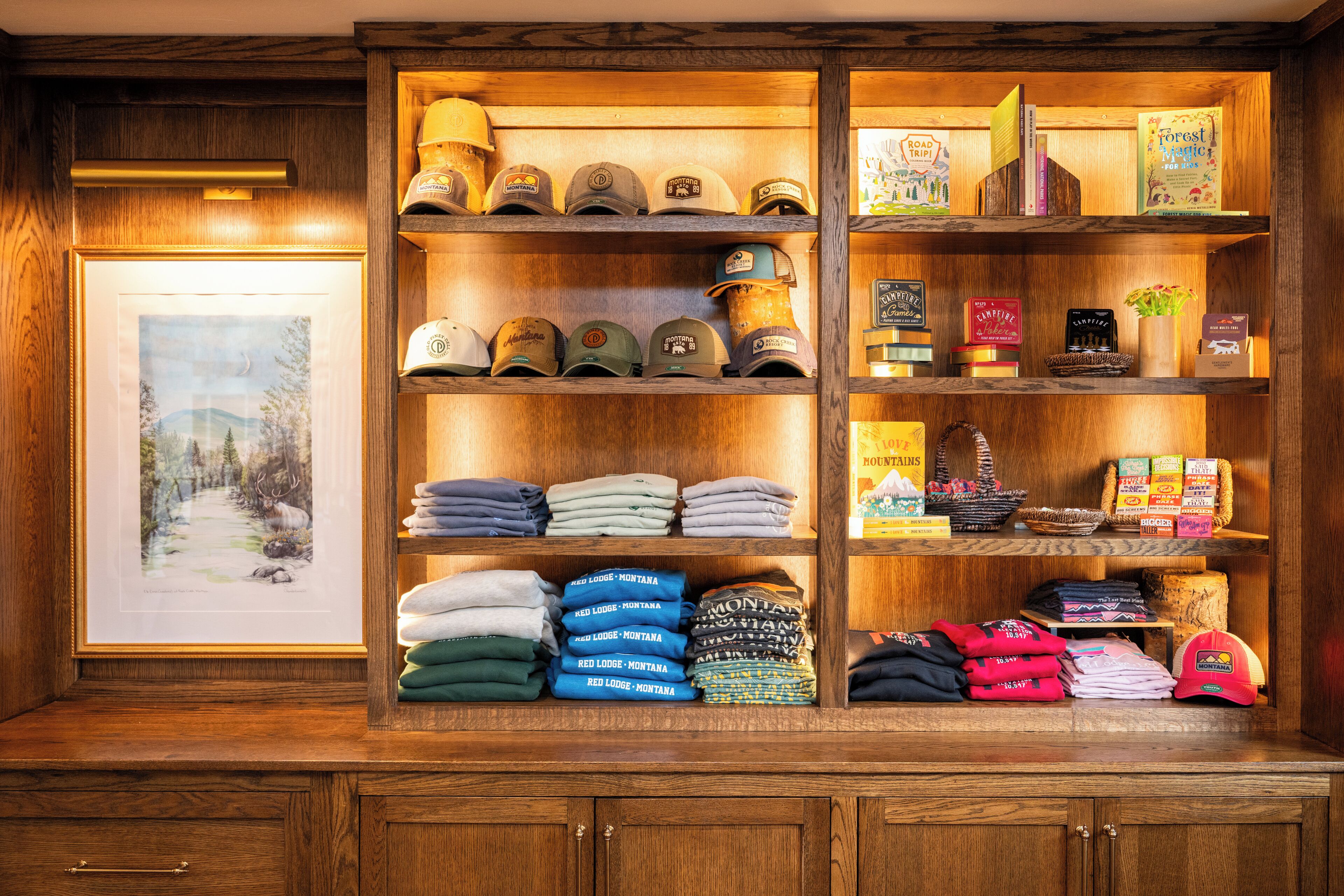 Een overzichtelijke presentatie van merchandise van Red Lodge Montana, waaronder hoeden, opgevouwen kleding en boeken.